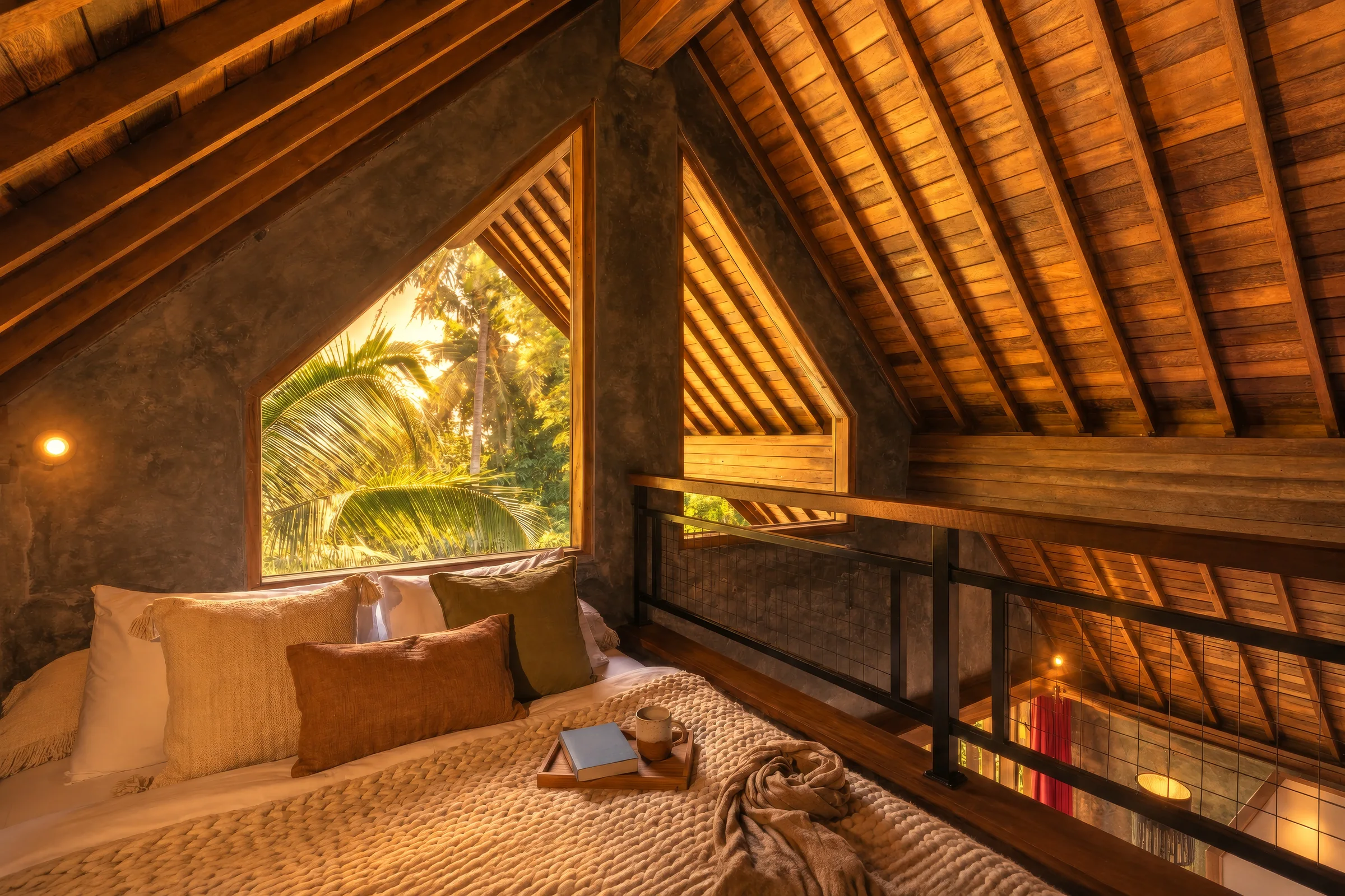 Queen bed beneath the exposed timber roof in the elevated mezzanine loft